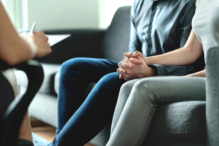couple holding hands while speaking to therapist